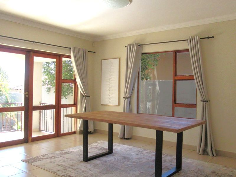 A bright dining room featuring tiled flooring and large wooden-framed glass doors that provide access to the outdoor area.