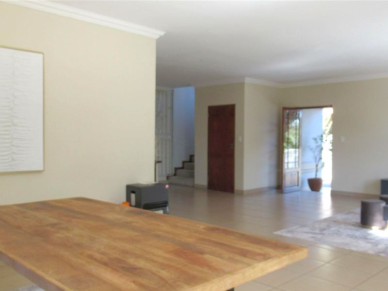 Spacious open-plan living area featuring neutral wall tones, tiled flooring, and classic cove cornicing, with direct access to an outdoor space.