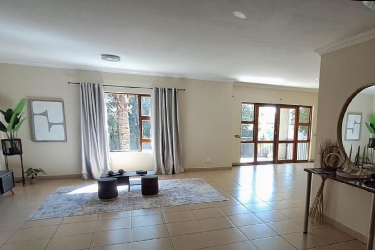 Spacious living area featuring neutral tiled flooring, large windows, and sliding glass doors providing natural light and access to the exterior.