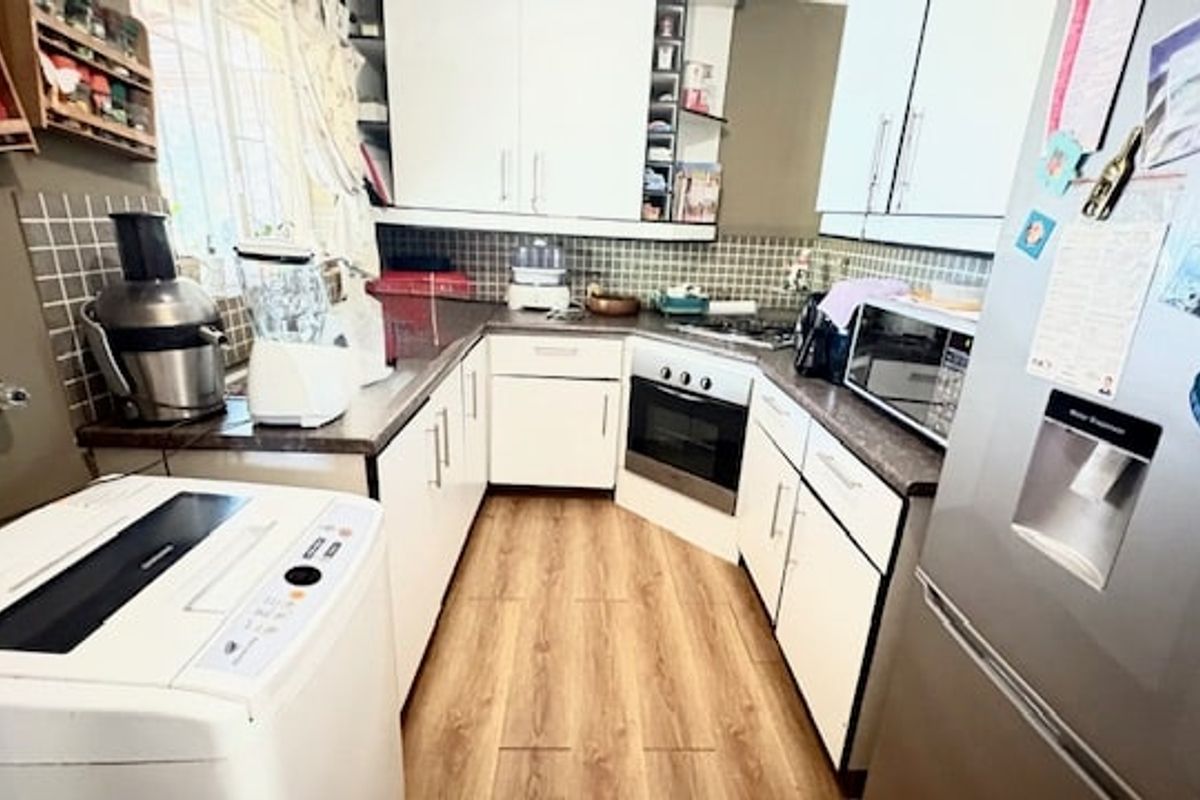 A functional kitchen featuring white cabinetry, laminate countertops, a tiled backsplash, and built-in cooking appliances with wood-look flooring.
