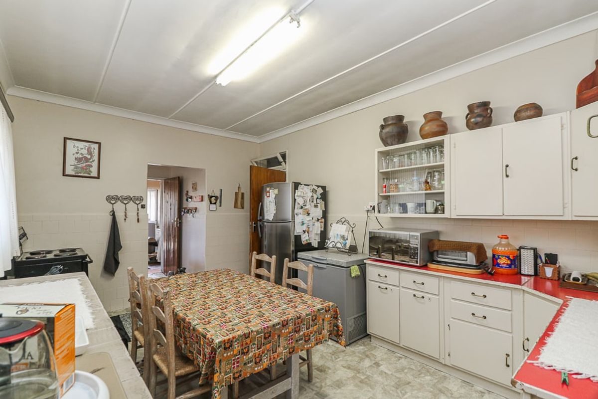 A functional kitchen featuring dated cabinetry, laminate countertops, and tiled splashbacks, offering potential for a modern renovation.