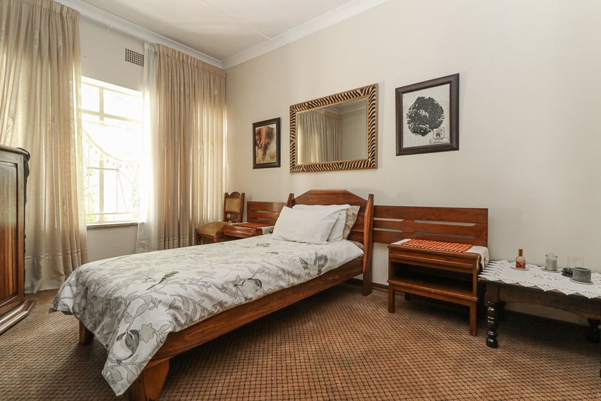 A bedroom featuring carpeted flooring, cornice detailing, and a window with natural light.