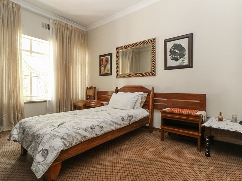 A bedroom featuring carpeted flooring, cornice detailing, and a window with natural light.