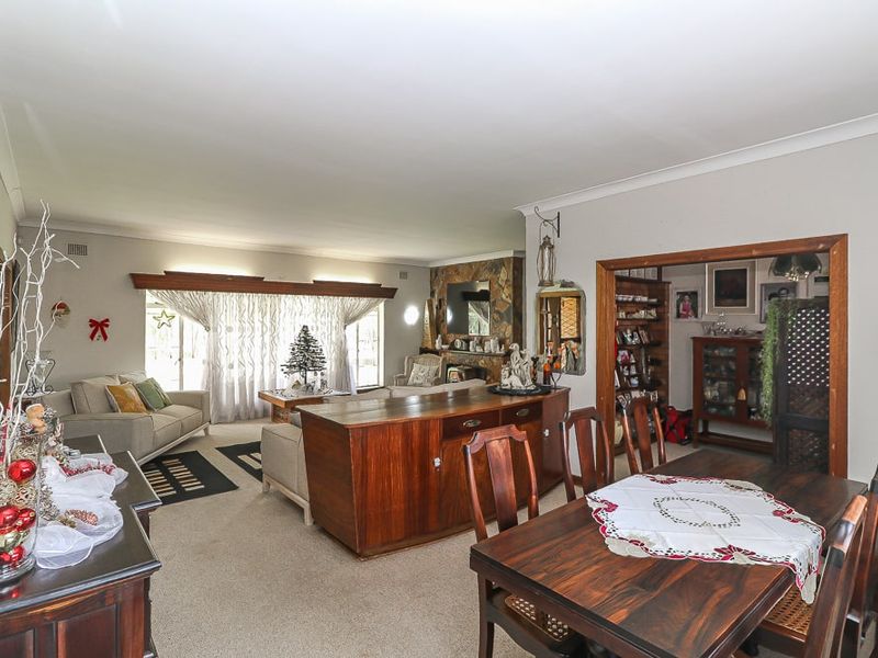Spacious open-plan living and dining area featuring a stone fireplace, neutral carpeting, and large sliding glass doors providing natural light.