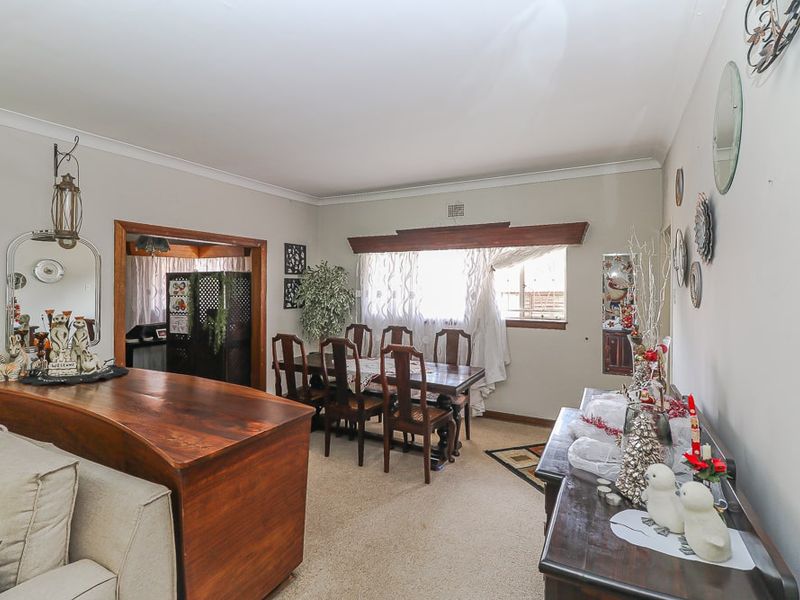 Open plan living and dining area featuring carpeted flooring, cove cornicing, and a timber window pelmet.