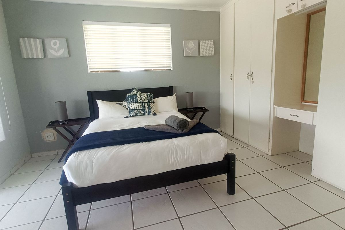 A bedroom featuring tiled flooring, built-in cupboards, and a built-in vanity area with a mirror.
