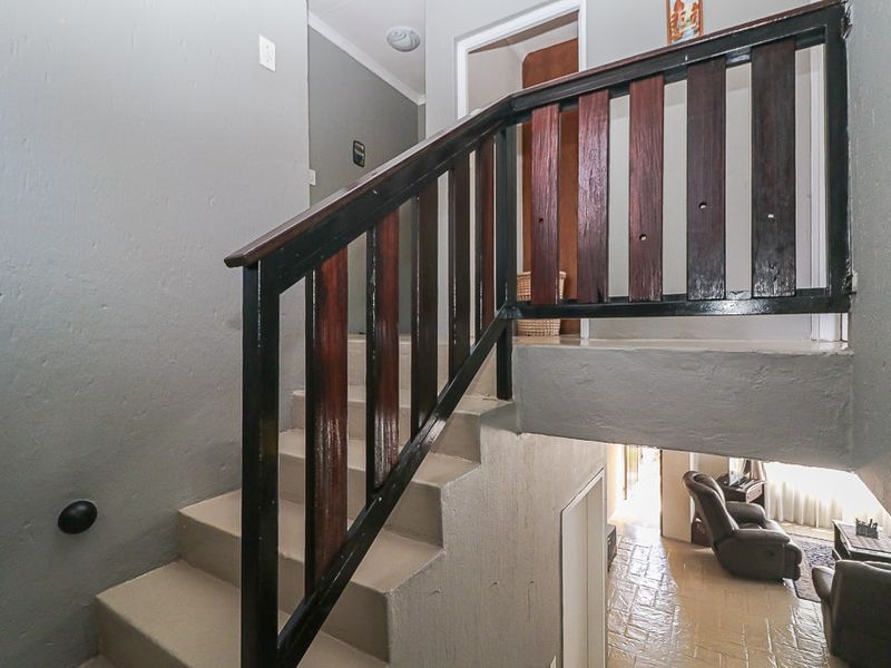Interior staircase featuring a dark timber balustrade and painted concrete steps, providing access between levels in the home.