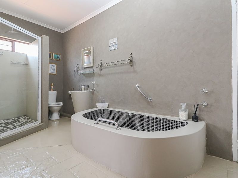 A bathroom featuring a custom built-in tiled bathtub, a separate glass-enclosed shower, a pedestal basin, and a toilet with neutral wall finishes.