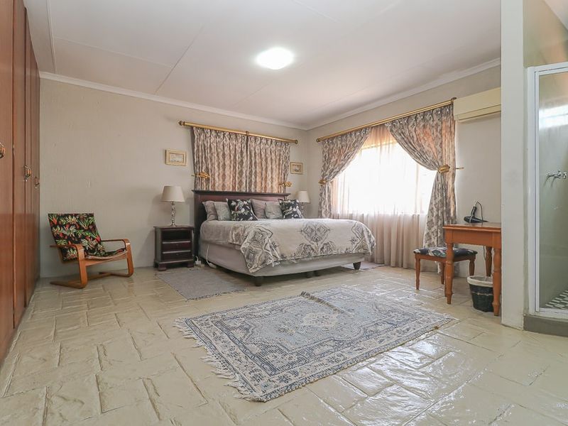 Spacious bedroom featuring built-in wooden wardrobes, tiled flooring, and an en-suite shower area.