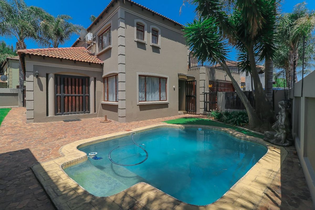Rear view of the property featuring a private swimming pool, paved patio area, and established garden surroundings.