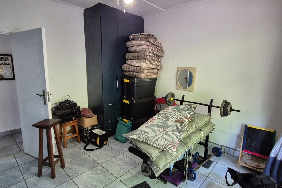 A bedroom featuring tiled flooring and a built-in wardrobe, currently utilized as a storage and utility space.
