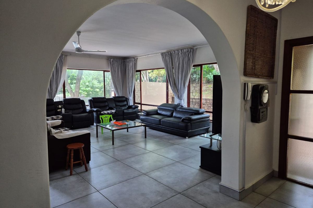 Spacious living room featuring large windows, tiled flooring, and a distinctive arched entryway, offering a bright and open atmosphere.