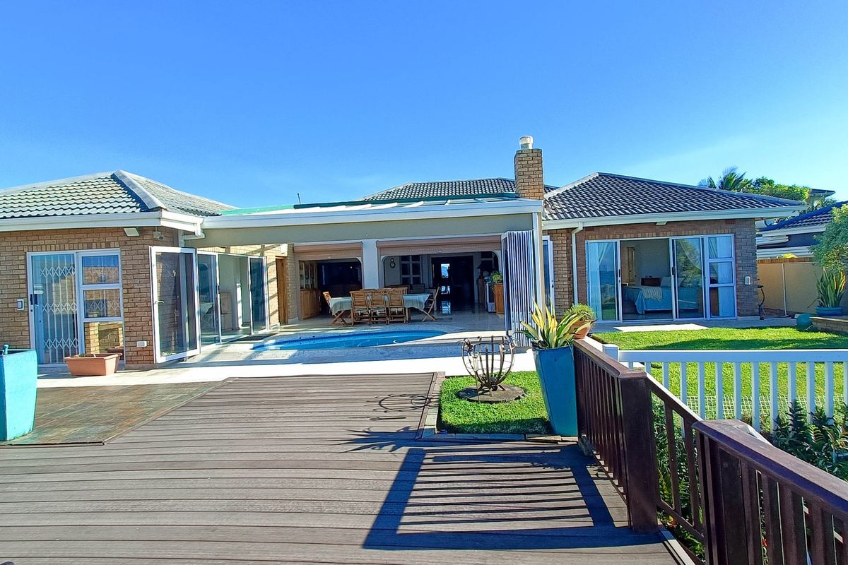 Rear view of the townhouse featuring a swimming pool, timber decking, covered patio area, and direct access to the living spaces through sliding glass doors.