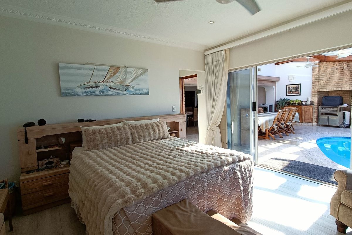 Spacious bedroom featuring a built-in headboard, crown molding, and large sliding glass doors providing direct access to the patio and pool area.
