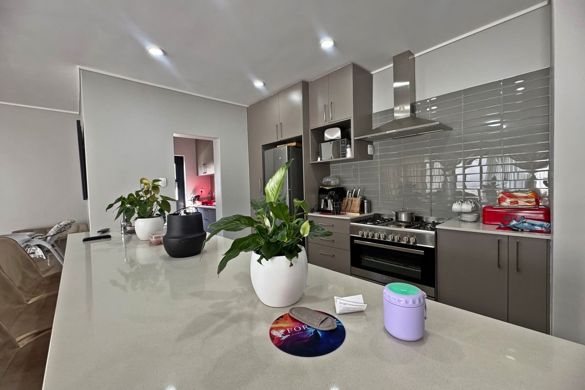 Modern kitchen featuring a large quartz island, gas stove with stainless steel extractor, subway tile backsplash, and ample built-in cabinetry.