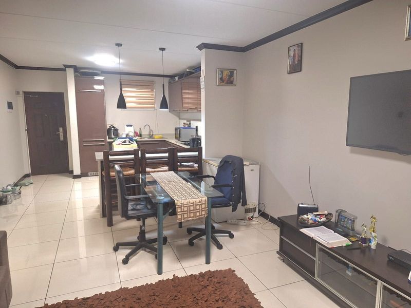 Open plan living and kitchen area featuring tiled flooring, modern cabinetry, and pendant lighting, creating a functional and connected living space.