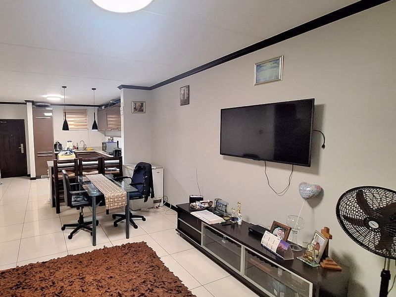 An open-plan living and kitchen area featuring tiled flooring, modern cabinetry, and a functional layout suitable for contemporary apartment living.