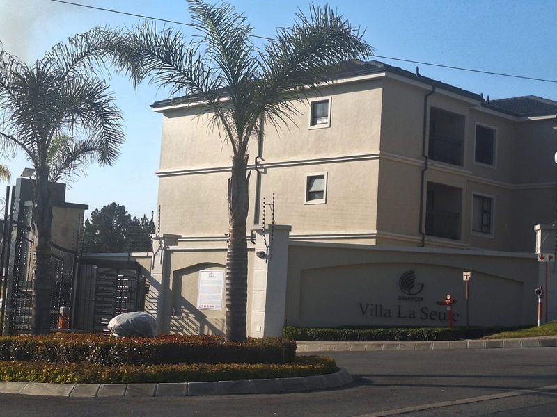 Exterior view of the Villa La Seute apartment complex entrance, featuring secure gated access, electric fencing, and well-maintained building facades.