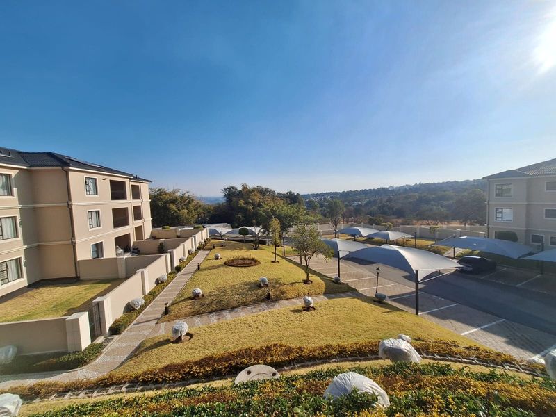 Elevated view of a well-maintained apartment complex featuring landscaped gardens, paved pathways, and covered parking bays.