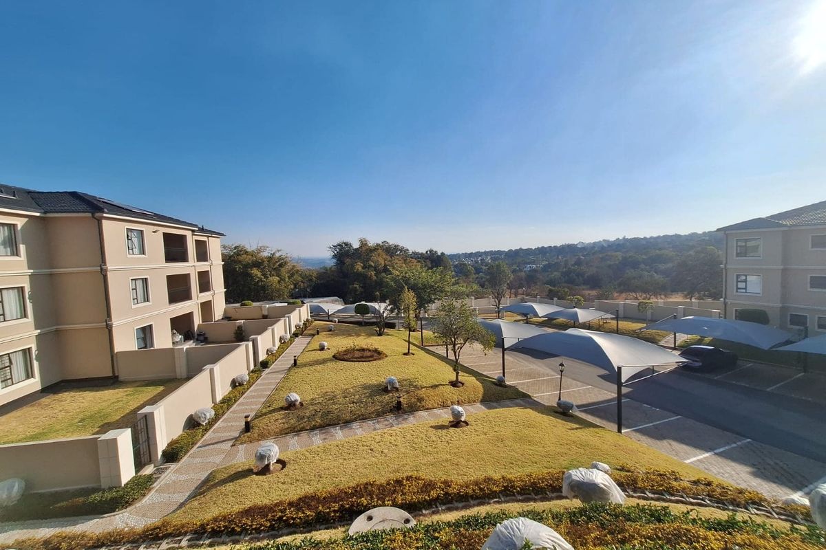 Elevated view of a well-maintained apartment complex featuring landscaped gardens, paved pathways, and covered parking bays.
