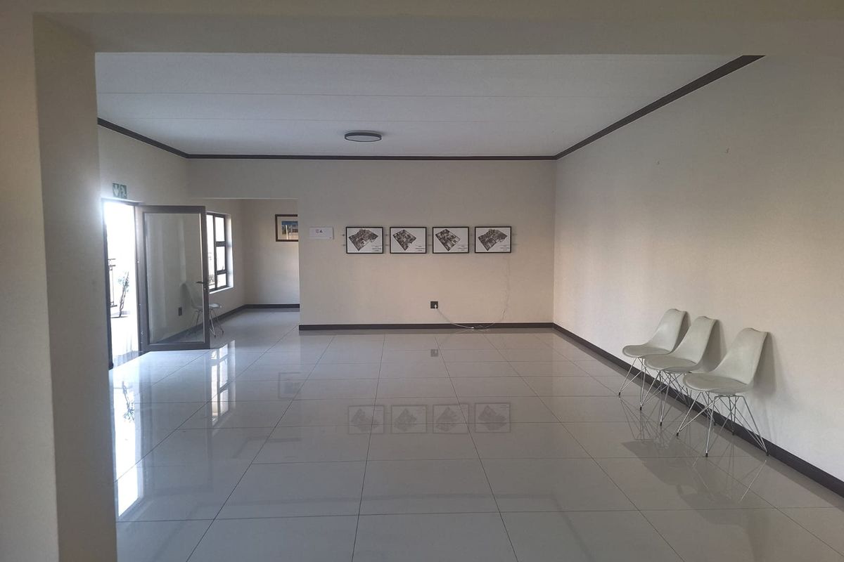 A spacious, open-plan living area featuring polished tile flooring, neutral walls, and clean architectural lines, offering a versatile blank canvas for interior design.