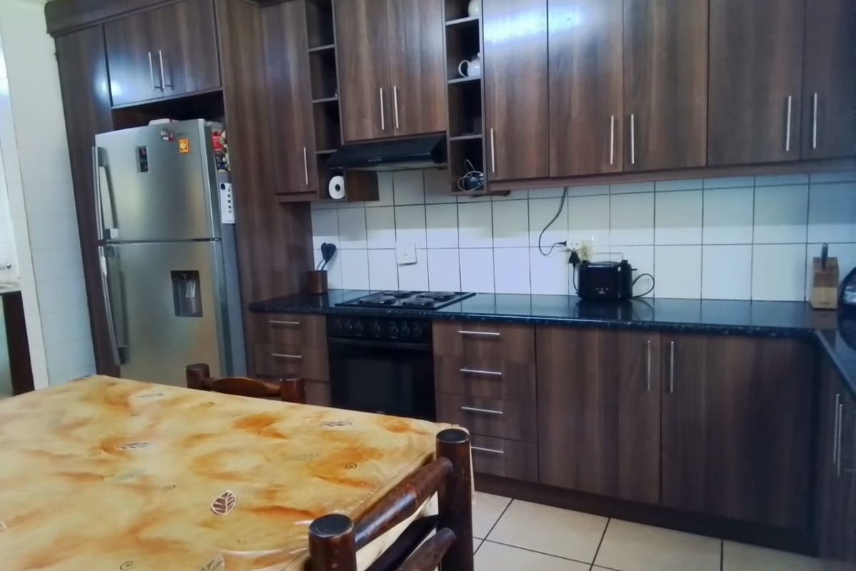 A functional kitchen featuring dark wood-look cabinetry, granite-style countertops, a built-in oven with gas hob, and a tiled backsplash.