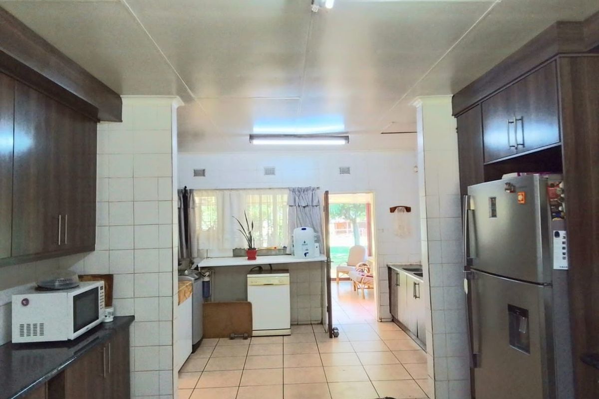 A functional kitchen featuring built-in cabinetry, tiled flooring, and a tiled splashback, with direct access to the outdoor area.
