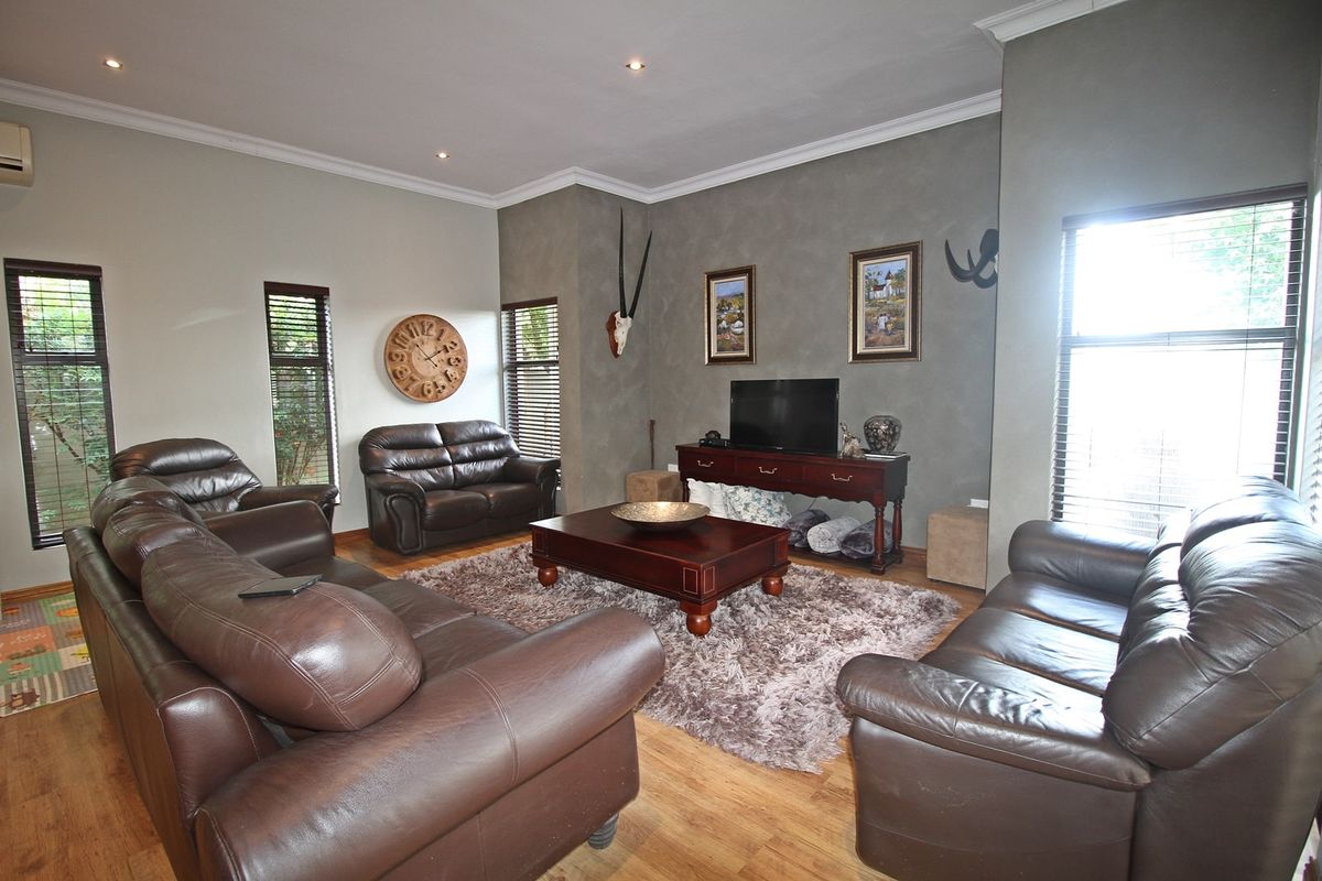 Spacious living room featuring timber flooring, recessed downlighting, and large windows with venetian blinds, creating a comfortable and well-lit family area.