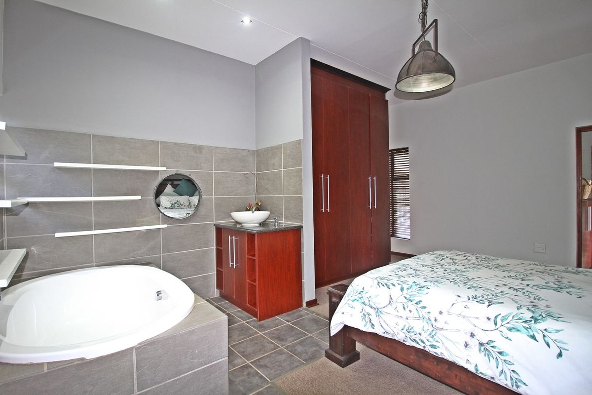 Spacious bedroom featuring an integrated en-suite bathroom area with a built-in bathtub, vanity, and ample built-in wardrobe storage.