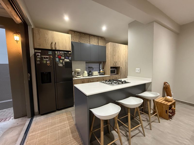 Modern kitchen featuring a central island with a gas hob, quartz countertops, two-tone cabinetry, and direct access to an outdoor patio area.