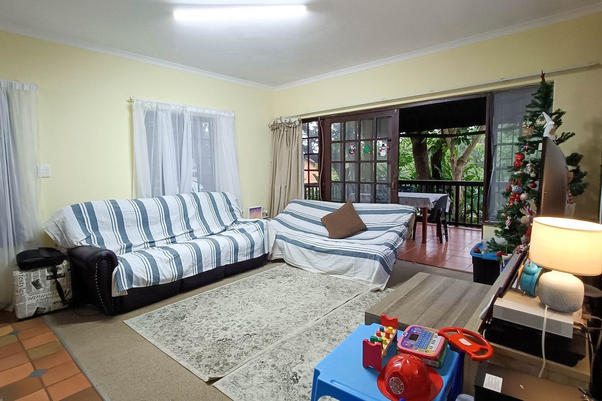A living room featuring sliding glass doors that open onto a covered patio, with a mix of carpet and tile flooring.