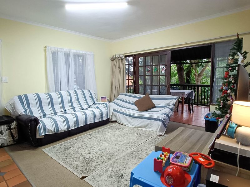 A living room featuring sliding glass doors that open onto a covered patio, with a mix of carpet and tile flooring.