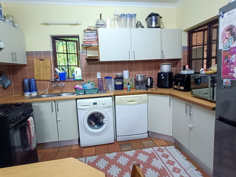 A functional kitchen featuring laminate countertops, tiled backsplash, built-in cabinetry, and a double basin sink with integrated laundry and dishwasher connections.