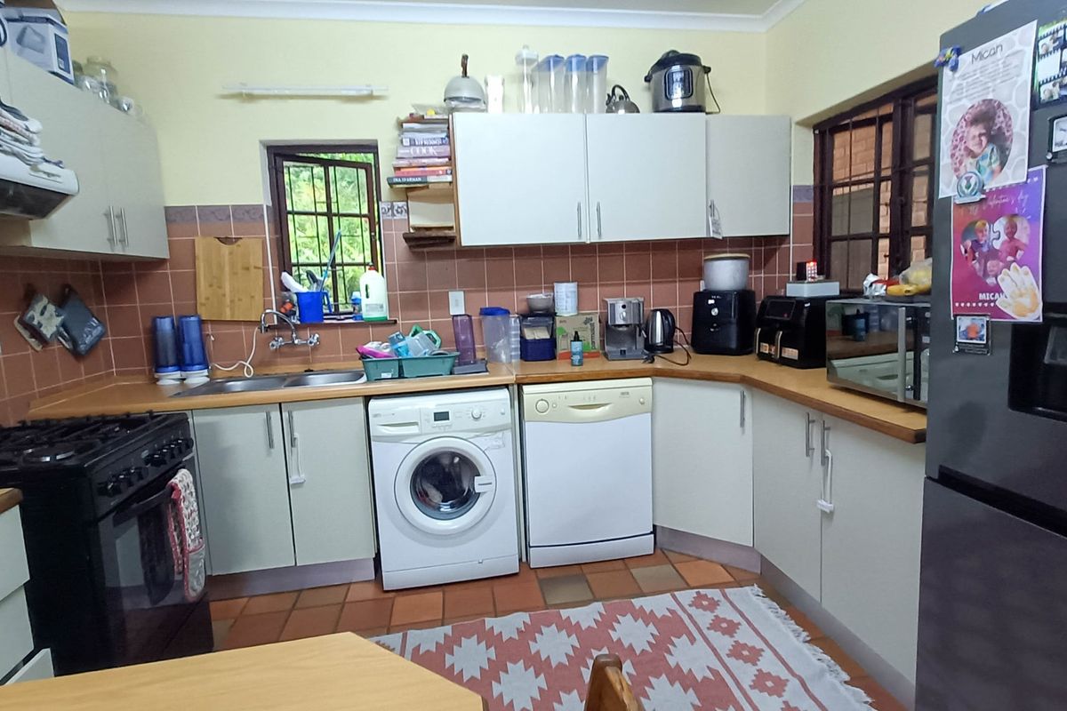 A functional kitchen featuring laminate countertops, tiled backsplash, built-in cabinetry, and a double basin sink with integrated laundry and dishwasher connections.