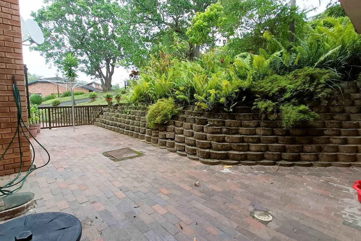 A rear courtyard featuring brick paving and a tiered retaining wall with established garden greenery, providing a private outdoor space.