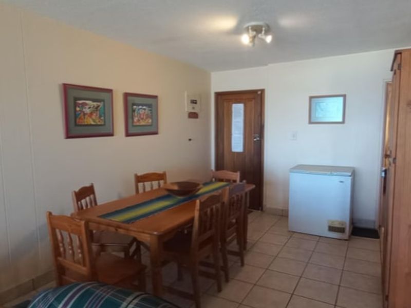 A functional dining area featuring tiled flooring and a wooden door, providing a simple and practical space for meals.
