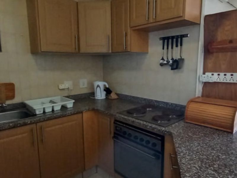 A functional kitchen featuring laminate cabinetry, a granite-look countertop, built-in oven, and electric hob, offering a practical layout for daily meal preparation.
