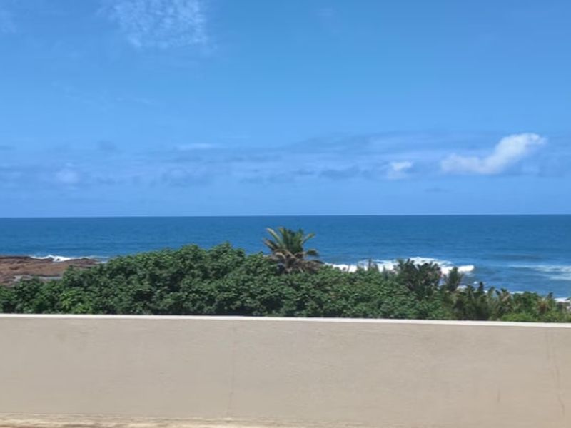 A clear, elevated view of the ocean and coastline from a balcony, showcasing the natural landscape and horizon.