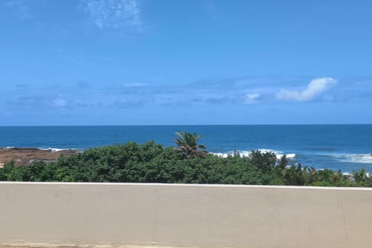 A clear, elevated view of the ocean and coastline from a balcony, showcasing the natural landscape and horizon.