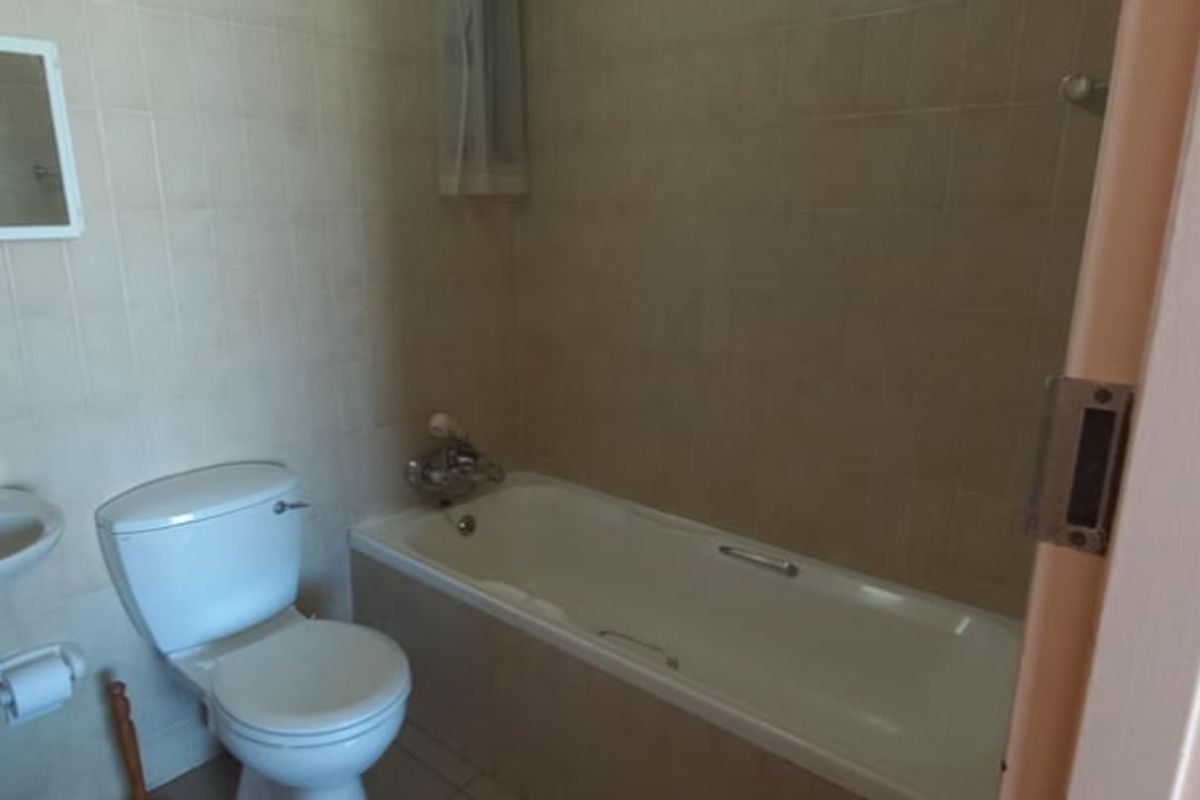 A functional bathroom featuring a pedestal basin, toilet, and a bathtub with wall tiling throughout.