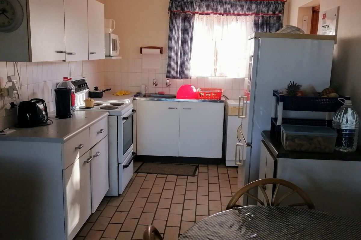 A functional kitchen featuring white cabinetry, tiled flooring, a tiled backsplash, and a freestanding stove, offering a practical layout for daily meal preparation.