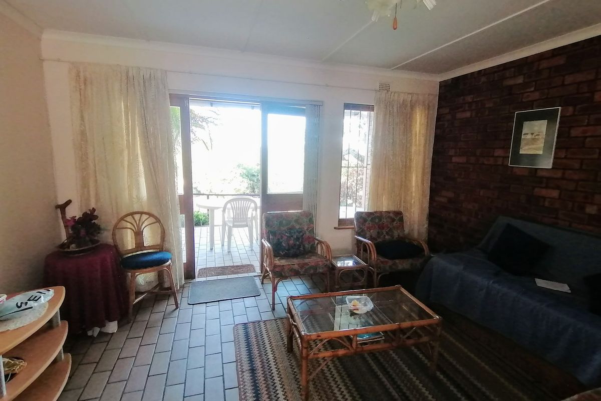A living room featuring an exposed brick wall, tiled flooring, and direct access to an outdoor patio area through sliding glass doors.