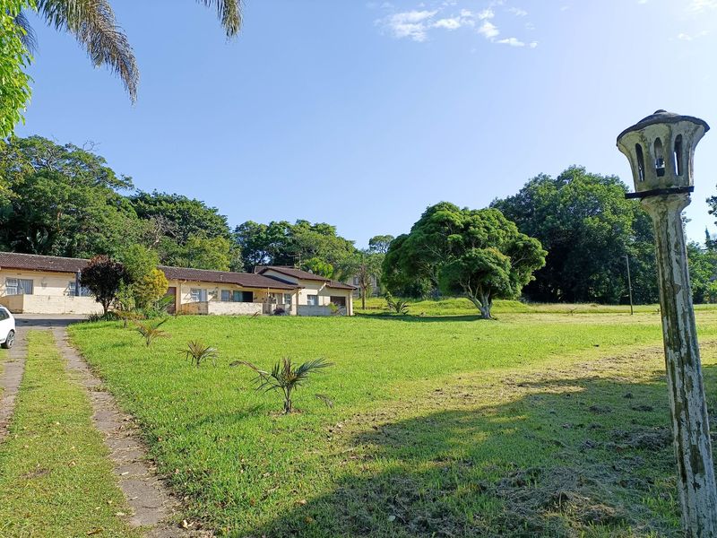 A view of the front exterior of the house, featuring a large lawn, concrete driveway, and a weathered garden lamp post.