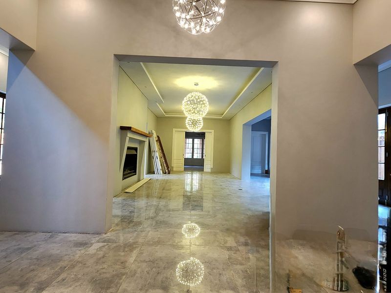 Spacious open-plan living area featuring polished stone flooring, recessed ceiling lighting, and a built-in fireplace, creating a bright and modern atmosphere.