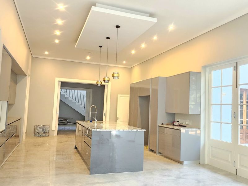 Modern open-plan kitchen featuring a central island with stone countertop, sleek cabinetry, recessed ceiling lighting, and direct access to the outdoor patio area.