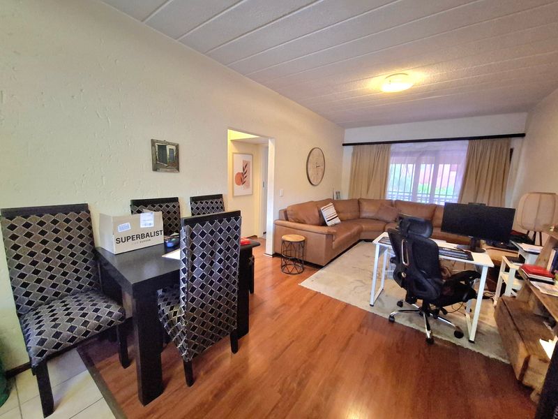 Open plan living and dining area featuring laminate flooring, textured walls, and a sliding glass door leading to an outdoor space.