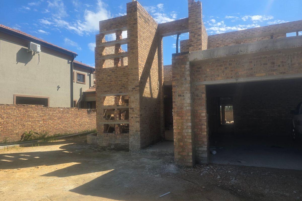 A residential property currently under construction, featuring exposed face brickwork and an incomplete garage structure.