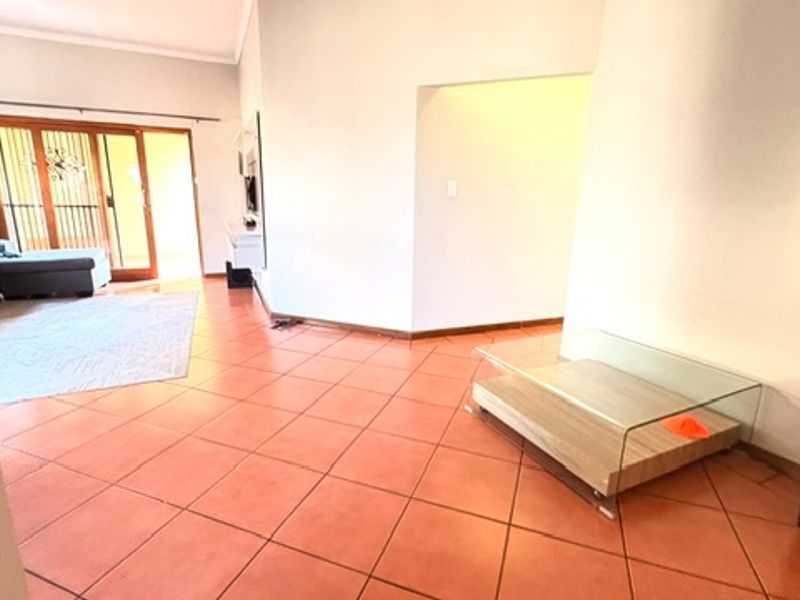 Spacious living area featuring terracotta floor tiles and a sliding glass door providing access to the outdoor patio.