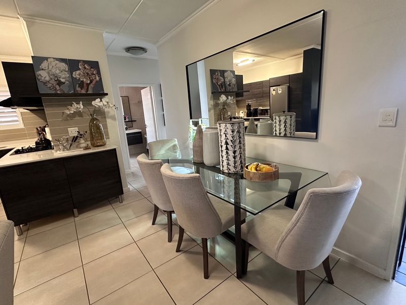 Open-plan dining area featuring tiled flooring, modern built-in cabinetry, and a gas hob, seamlessly connecting to the kitchen and adjacent living spaces.