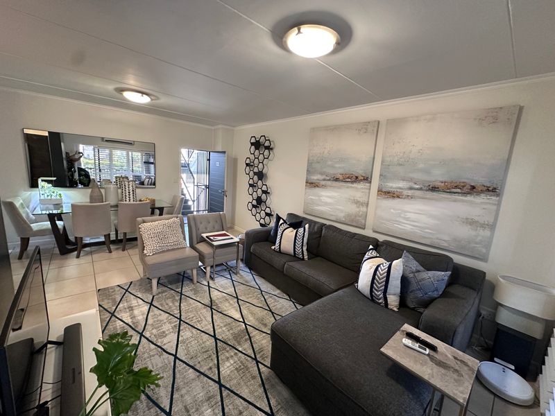 An open-plan living and dining area featuring tiled flooring, neutral walls, and a split-system air conditioning unit, providing a bright and functional living space.